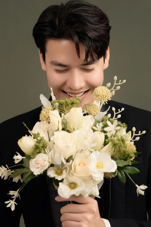 Chú rể cầm hoa cưới trong bộ ảnh studio